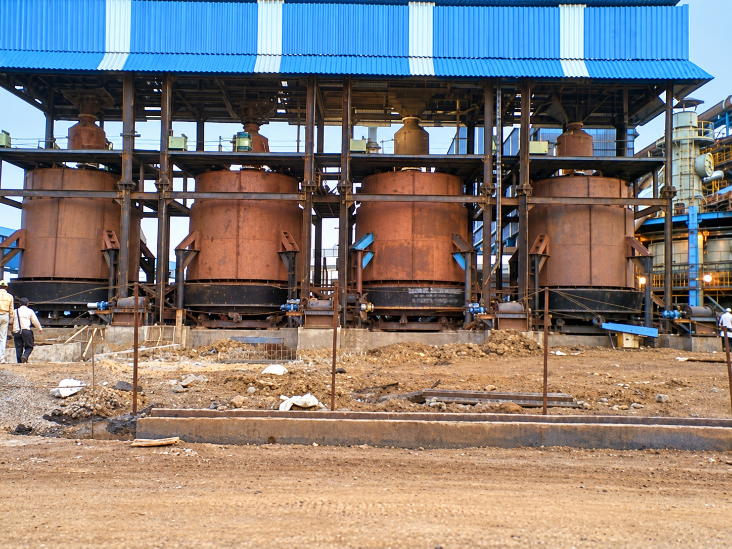 Four Rusty Industrial Vessels Beneath Blue Roof